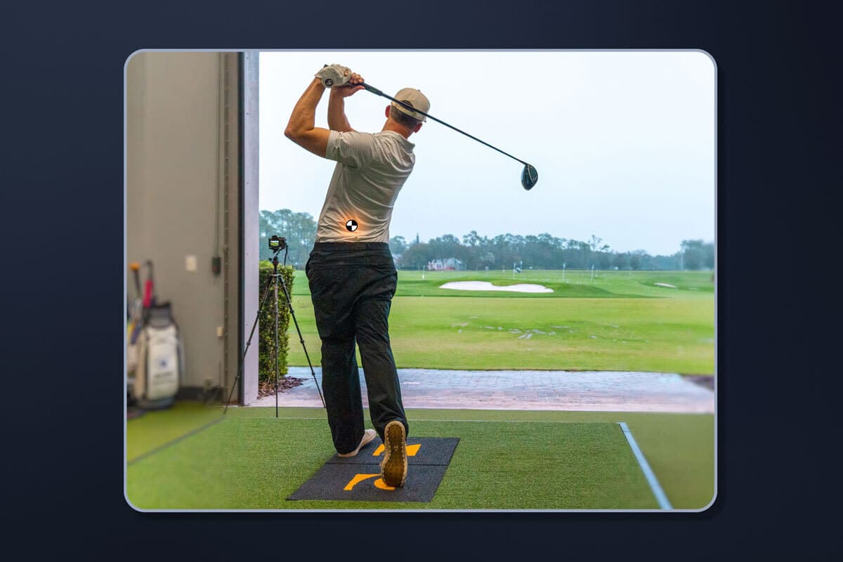 Golfer taking a swing on sensor plates in a golf bay with background